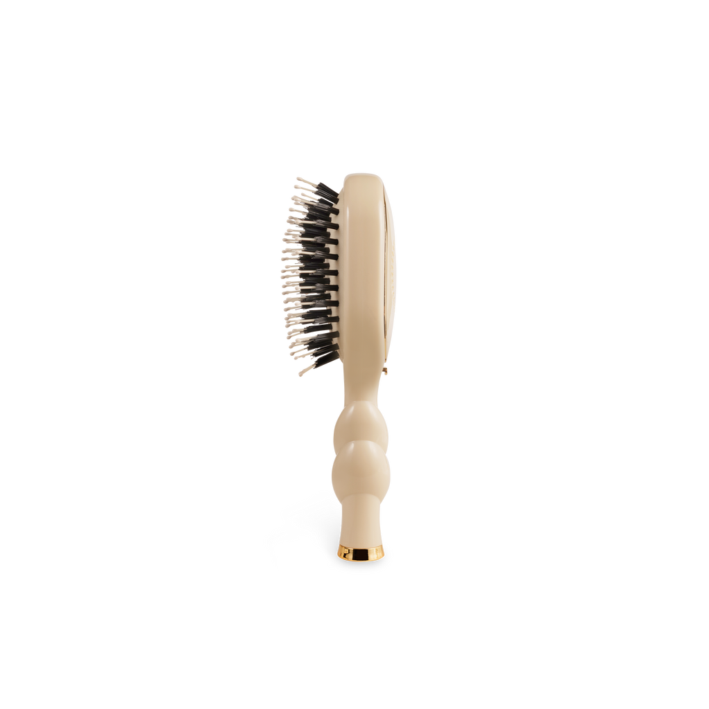 Beige hairbrush with black bristles on a white background