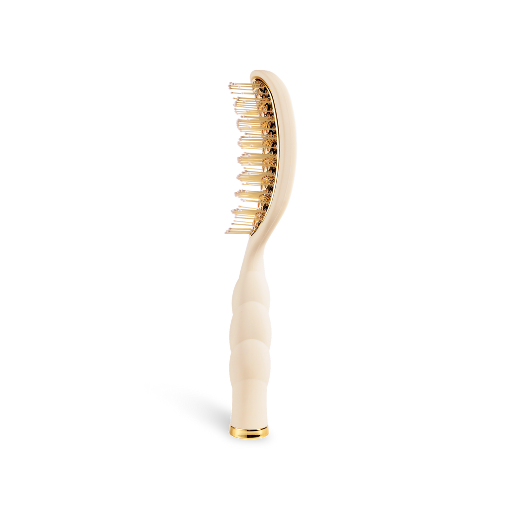 Hairbrush with gold bristle head and white handle on a white background