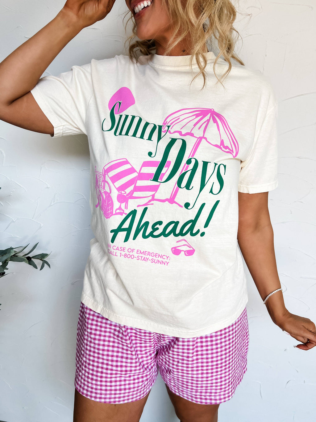 Person wearing a white t-shirt with 'Sunny Days Ahead!' graphic and pink shorts.