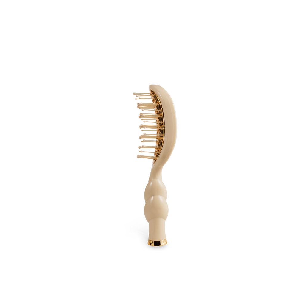 Beige hairbrush with gold bristle head on a white background